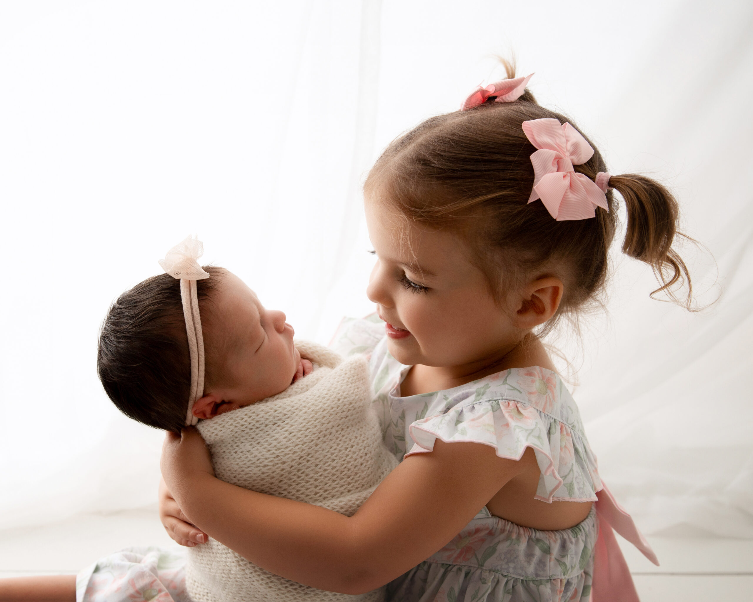 big sister holding baby sister in a precious portrait